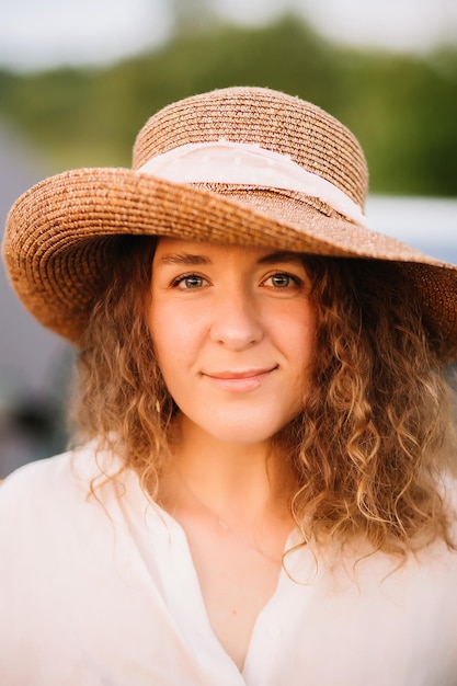 Mooie jonge vrouw met krullend haar met hoed Zonsondergang of zonsopgang helder avondlicht