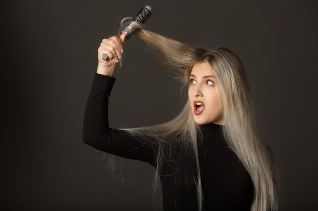 Mooie jonge vrouw met lang haar op een witte achtergrond kamt haar haar