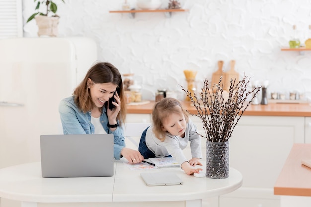 Mooie jonge vrouw met laptop en haar dochter communiceren thuis via video met familie