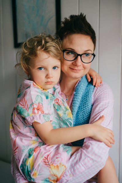 Mooie jonge vrouw met mooi gezicht, kort donker haar, grote ogen houdt haar kind vast en verheugt zich