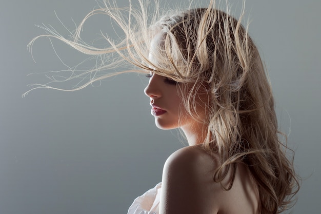 Mooie jonge vrouw met mooie oorbellen, portret close-up. vliegend haar