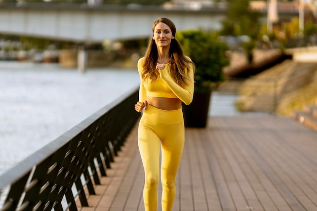 Mooie jonge vrouw met oefening op de pier aan de rivier