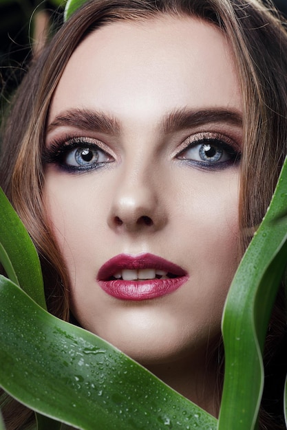 Mooie jonge vrouw met perfecte huid en natuurlijke make-up Tienermodel met groene bladeren