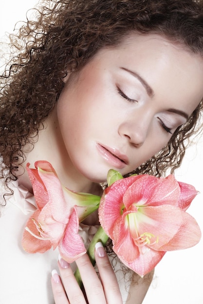 Mooie jonge vrouw met roze bloem op een witte achtergrond