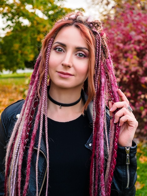 Mooie jonge vrouw met roze kanekalon dreadlocks camera kijken en glimlachen