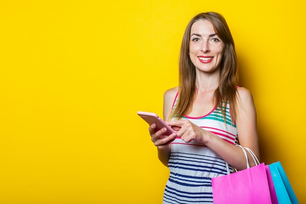 Mooie jonge vrouw met telefoon en boodschappentassen