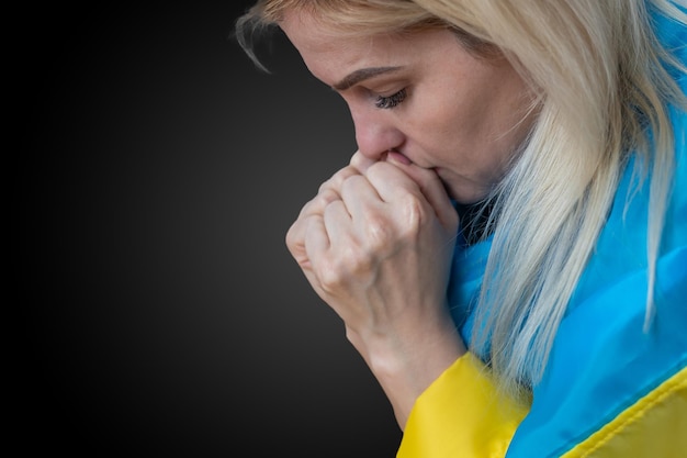 Mooie jonge vrouw met vlag van Oekraïne op donkere close-up als achtergrond