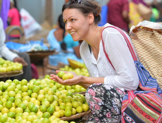 Mooie jonge vrouw met weinig citroenen in handen op de markt