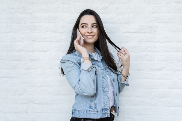 Mooie jonge vrouw met zwart haar praten aan de telefoon en glimlachen