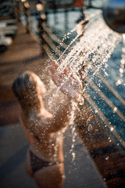 Mooie jonge vrouw neemt een ontspannende douche in een zwembroek op een zonnige dag buiten aan zee. Het meisje op vakantie rust. Selectieve focus