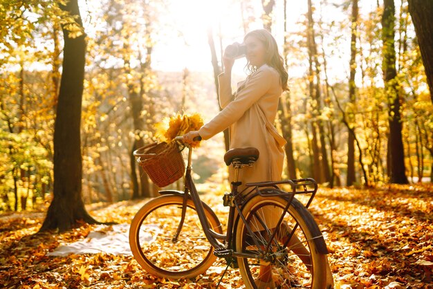 Mooie jonge vrouw neemt foto's met een retro camera in het herfstbos en geniet van het herfstweer