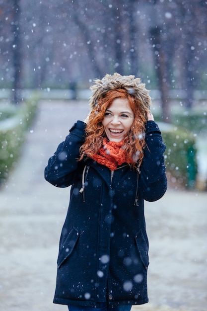 Mooie jonge vrouw onder de sneeuw in het park