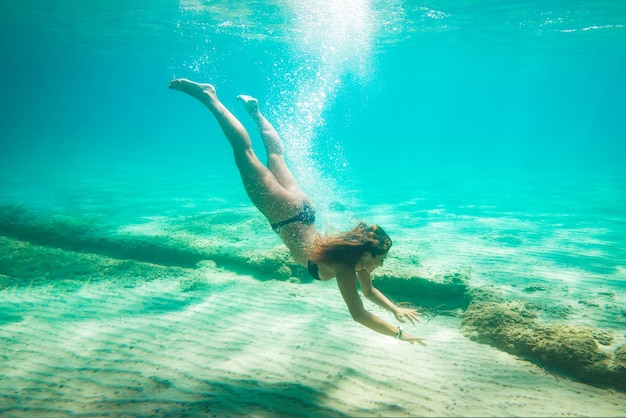 Mooie jonge vrouw onderwater duiken in de zee.