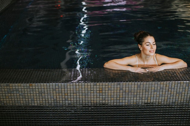 Mooie jonge vrouw ontspannen aan het zwembad van het binnenzwembad