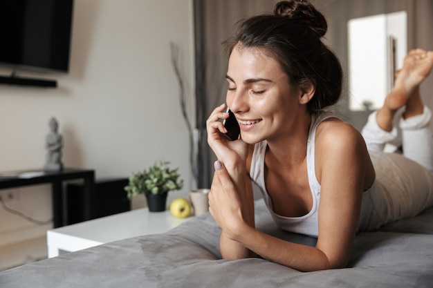 Mooie jonge vrouw ontspannen op een bank thuis, praten over de mobiele telefoon