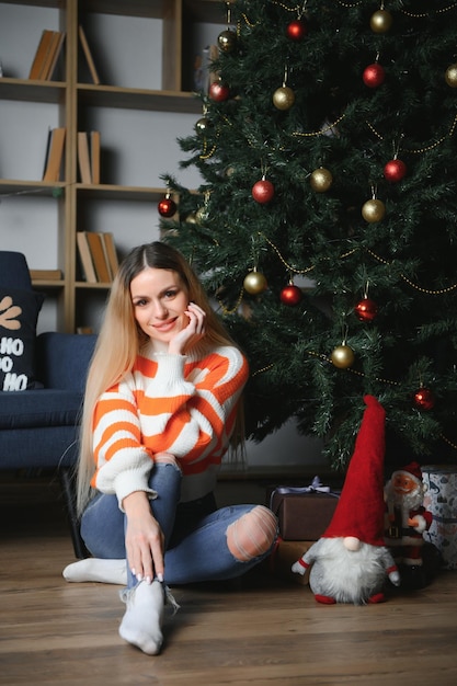 Mooie jonge vrouw ontspannen thuis op eerste kerstdag