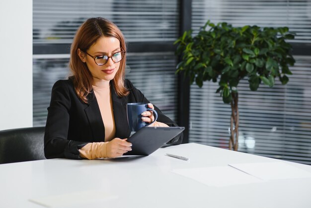 Mooie jonge vrouw op de werkplek met behulp van een digitale tablet