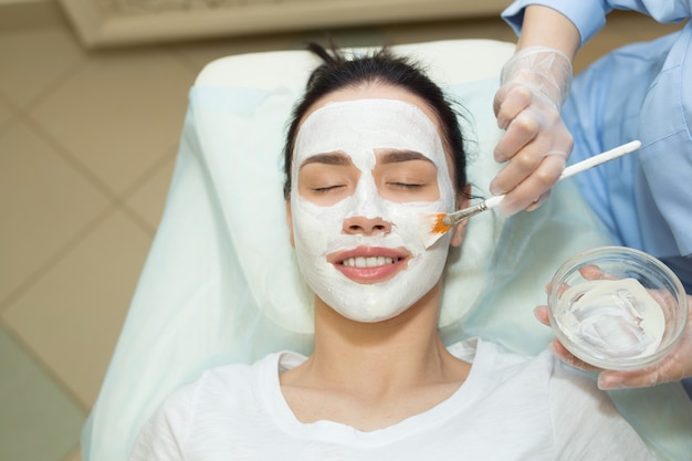 mooie jonge vrouw op een gezichtsbehandeling in een schoonheidssalon een crème toe te passen