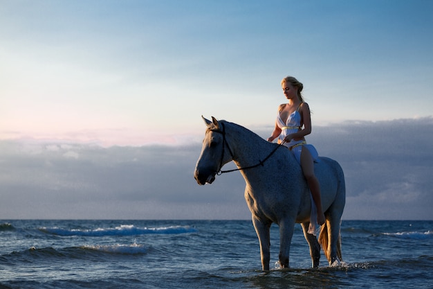 Mooie jonge vrouw op een paard dichtbij het overzees