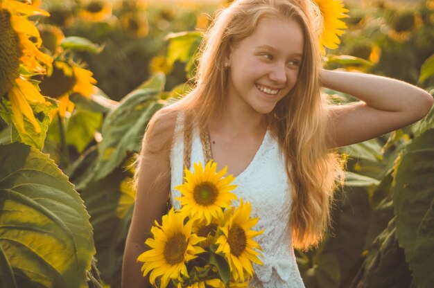 Mooie jonge vrouw op een zonnebloemgebied. Portret van een jonge vrouw in de zon. Stuifmeelallergieën concept