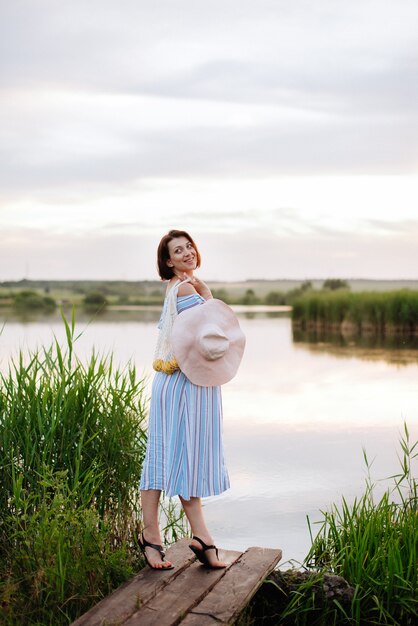 Mooie jonge vrouw op het meer bij zonsondergang