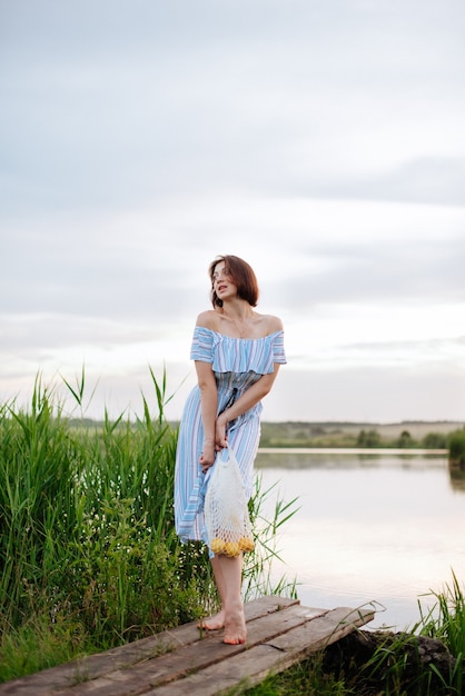 Mooie jonge vrouw op het meer bij zonsondergang