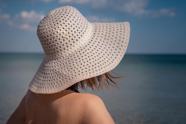 Mooie jonge vrouw op het strand met hoed