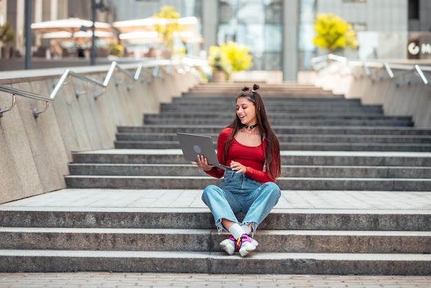 Mooie jonge vrouw op straat met behulp van laptop