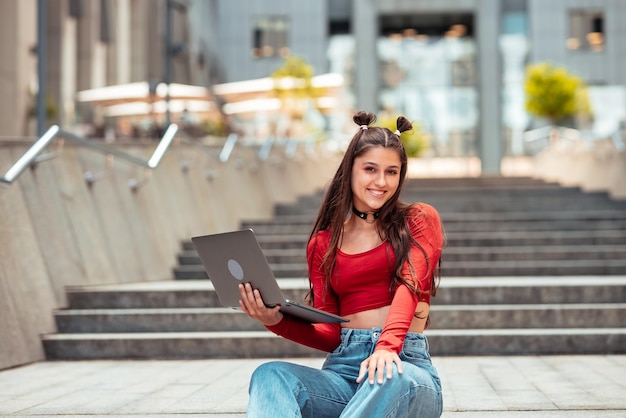 Mooie jonge vrouw op straat met behulp van laptop