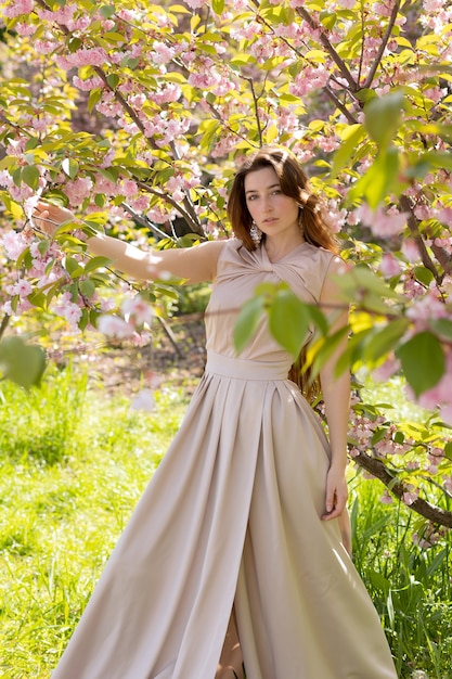 Mooie jonge vrouw poseren in een bloeiende sakura-tuin.