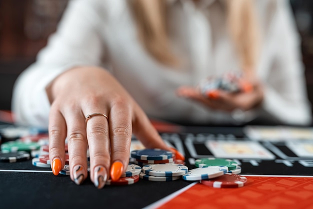 Mooie jonge vrouw speelt poker in het casino, speelt kaarten met fiches.