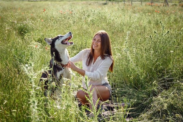 Mooie jonge vrouw spelen met grappige husky hond buiten in het park