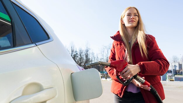 Mooie jonge vrouw tanken auto bij mooi weer