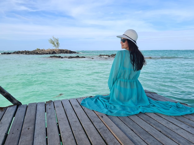 Mooie jonge vrouw zit op houten pier tropisch strand steiger op eiland Maldiven of Mauritius