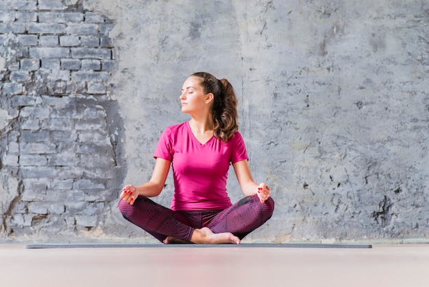 Foto mooie jonge vrouw zitten in yoga-positie mediteren