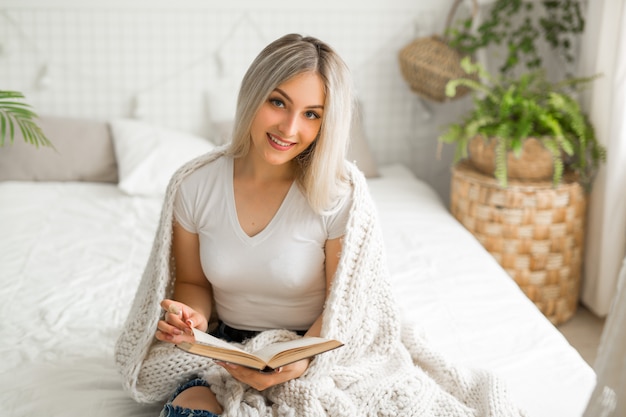 mooie jonge vrouw zittend op bed met een boek