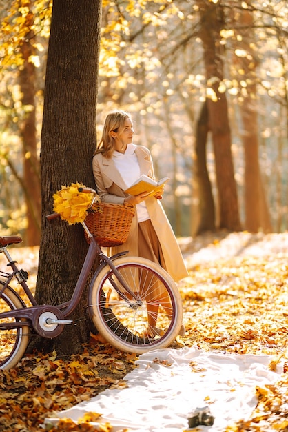 Mooie jonge vrouw zittend op een gevallen herfst bladeren in een park lezen van een boek Ontspanning