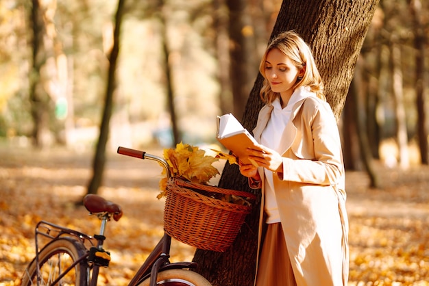 Mooie jonge vrouw zittend op een gevallen herfst bladeren in een park lezen van een boek Ontspanning