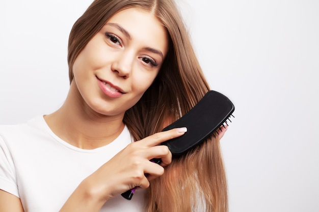 Mooie jonge vrouw zorgt voor haar haar, lang haar kammen met een kam