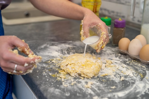 Mooie jonge vrouwelijke handen breken eieren tot meel om een mooi deeg te kneden Kookconcept