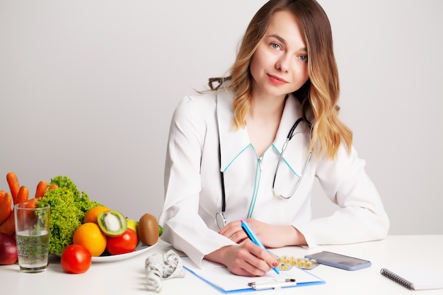 Mooie jonge vrouwelijke voedingsdeskundige met verse groenten en fruit