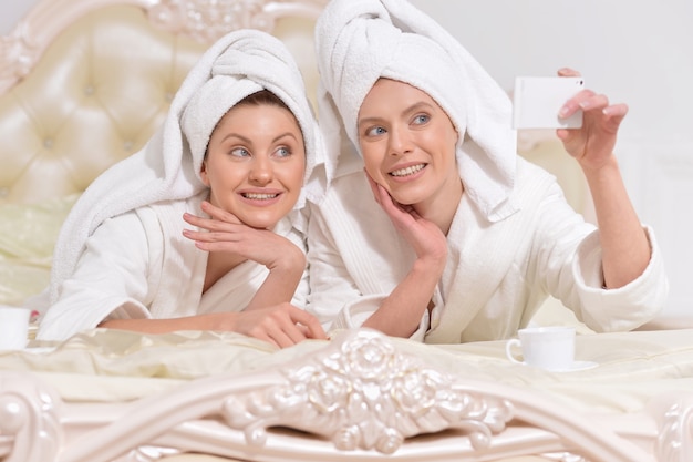 Mooie jonge vrouwen die witte badjassen dragen die selfie doen