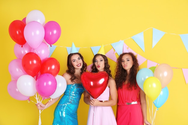 Mooie jonge vrouwen met luchtballons op gele oppervlakte