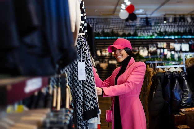 Mooie jonge vrouwenkoper die kleding kiest uit een rek in een kledingwinkel