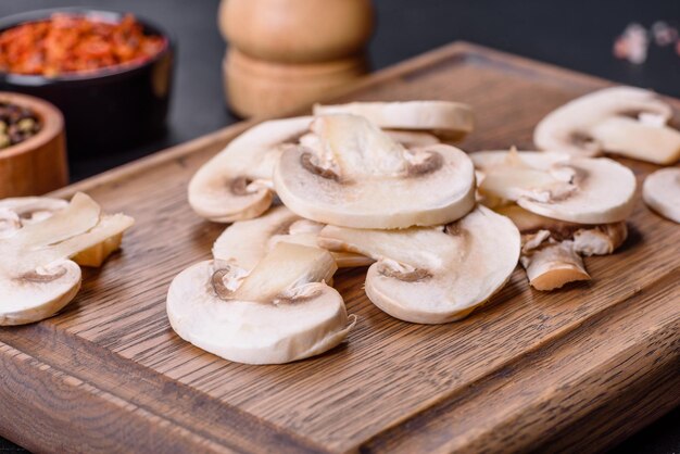 Mooie jonge witte champignons in plakjes gescheurd op een donkere betonnen ondergrond