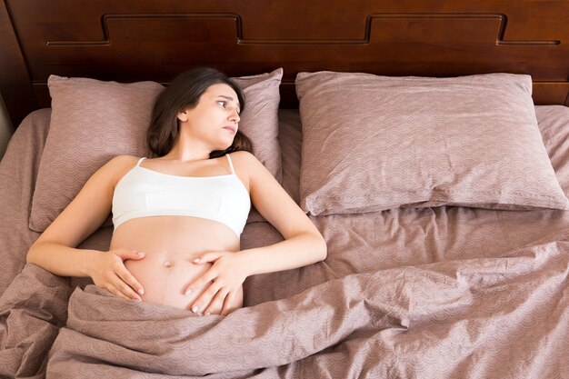 Foto mooie jonge zwangere vrouw ligt in bed top view het meisje lijdt dat haar man haar heeft verlaten