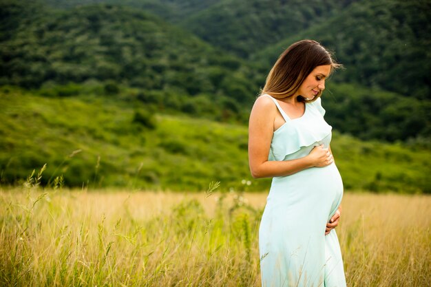 Mooie jonge zwangere vrouw ontspannen buiten in de natuur op zomerdag