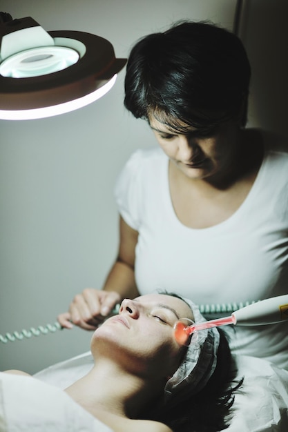 Mooie jongedame die cosmetisch gezichtsmasker ontvangt in de schoonheidssalon van de spa en ontspant