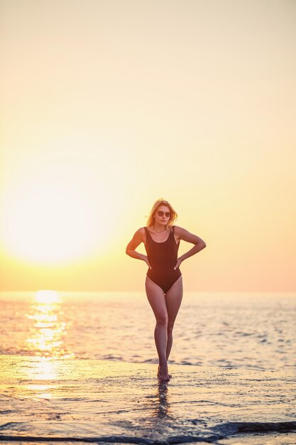 Mooie jongedame genieten van de wind op het strand Portret van een zorgeloos meisje ontspannen aan de zee Mooie lachende vrouw genieten van de zon op het strand