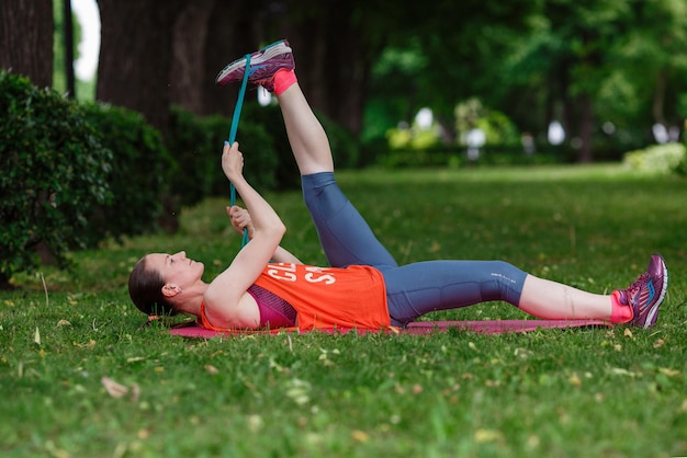 Mooie jongedame mediteert op een zomerdag in het park Idee en concept van rust in een drukke stad en een gezonde levensstijl die zich uitstrekt en zich voorbereidt op een run in het park